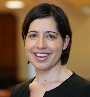 Smiling woman with short dark hair. She is wearing a black shirt and small earings.